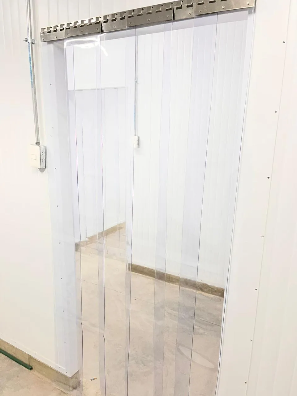 Acceso a una cámara frigorífica con cortina nueva de lamas de PVC y riel de acero inoxidable